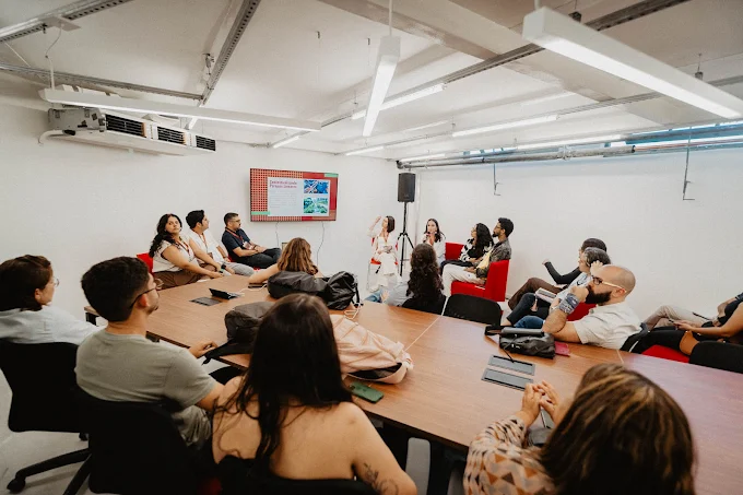 Pessoas reunidas ao redor de uma mesa durante uma apresentação