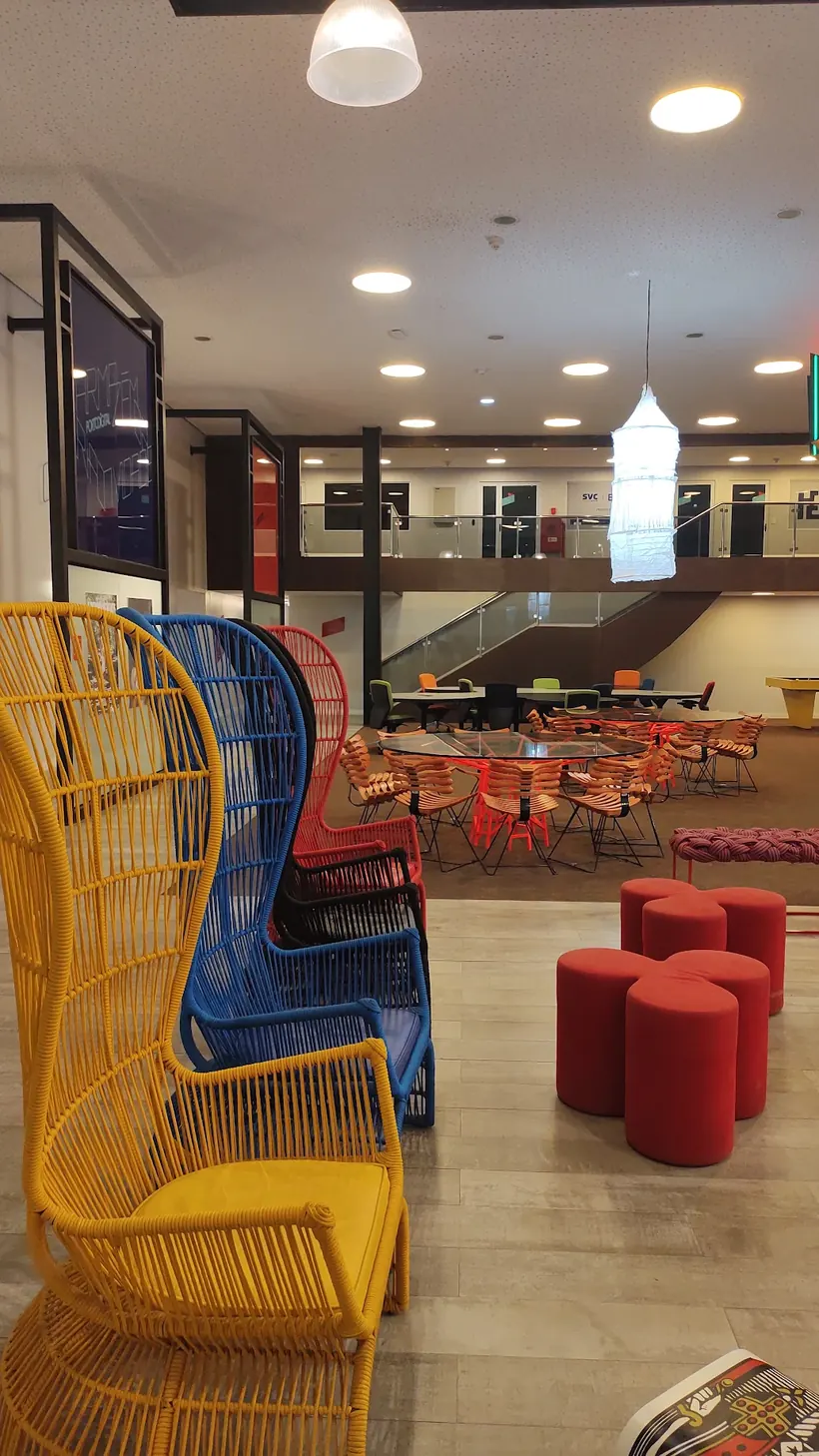 Espaço de convivência com poltronas coloridas, mesas e mezanino