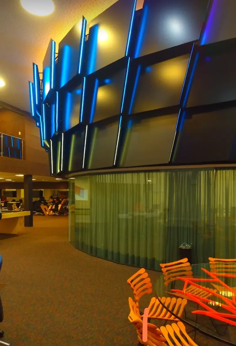 Ambiente de trabalho com mesas, cadeiras e painéis iluminados em azul